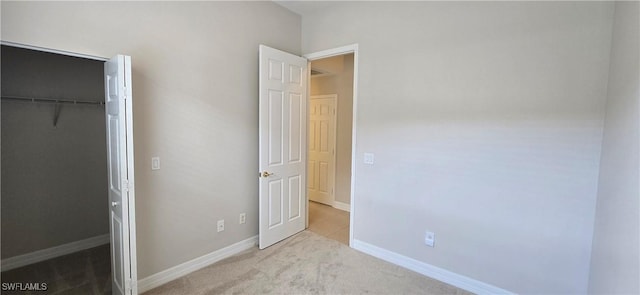 unfurnished bedroom featuring a walk in closet, light carpet, and a closet