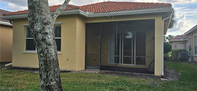 rear view of property featuring a sunroom, central AC unit, and a lawn