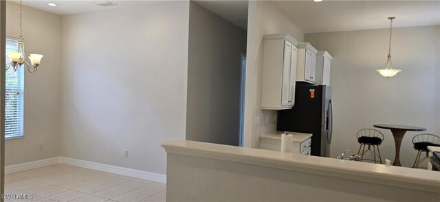 kitchen with pendant lighting, an inviting chandelier, stainless steel refrigerator with ice dispenser, white cabinets, and light tile patterned flooring