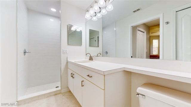 bathroom with toilet, vanity, tile patterned flooring, and tiled shower