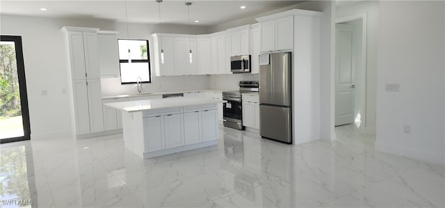 kitchen with sink, hanging light fixtures, a kitchen island, white cabinetry, and stainless steel appliances