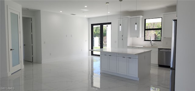 kitchen featuring pendant lighting, plenty of natural light, a kitchen island, and white cabinetry