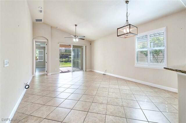 tiled empty room featuring lofted ceiling and ceiling fan with notable chandelier