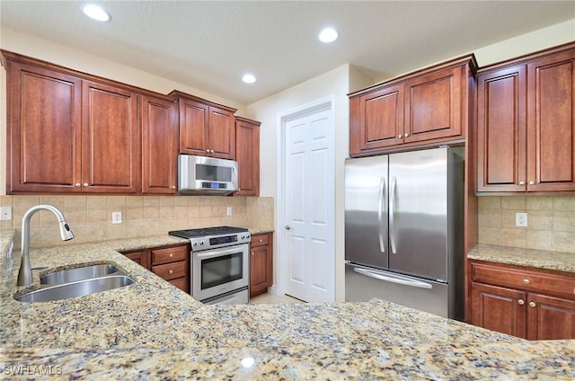 kitchen with sink, backsplash, stainless steel appliances, and light stone countertops