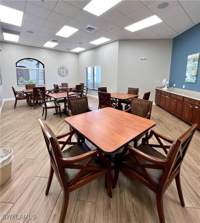 dining space featuring light hardwood / wood-style floors and a drop ceiling