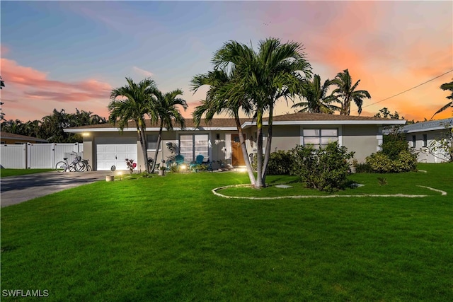 ranch-style home featuring a garage and a lawn