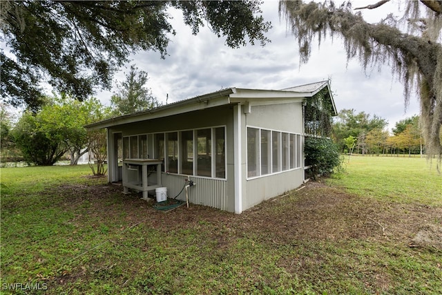 view of side of home featuring a sunroom and a lawn