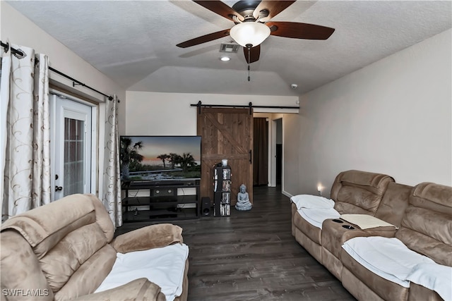 living room with a barn door, a textured ceiling, dark hardwood / wood-style floors, vaulted ceiling, and ceiling fan