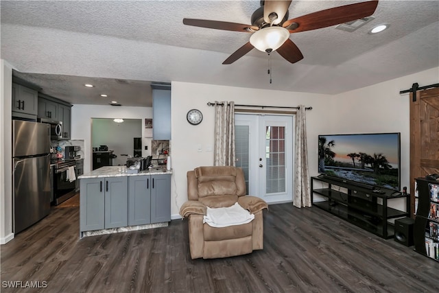 living room featuring a barn door, a textured ceiling, and dark hardwood / wood-style flooring