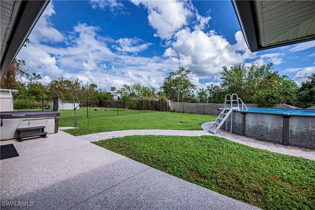 view of yard with a patio and a swimming pool with hot tub