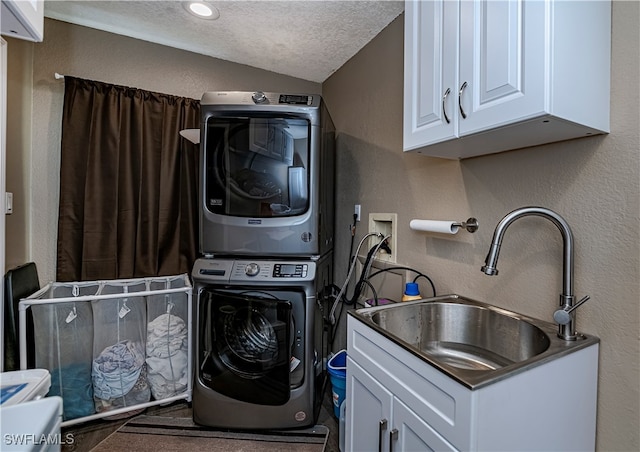 laundry room featuring stacked washer and dryer, a textured ceiling, and sink