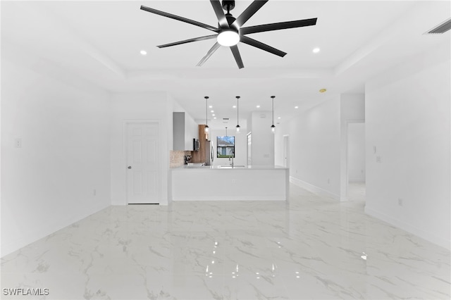 unfurnished living room with ceiling fan, a tray ceiling, and sink