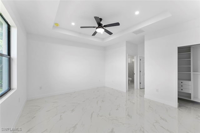 spare room featuring a raised ceiling and ceiling fan