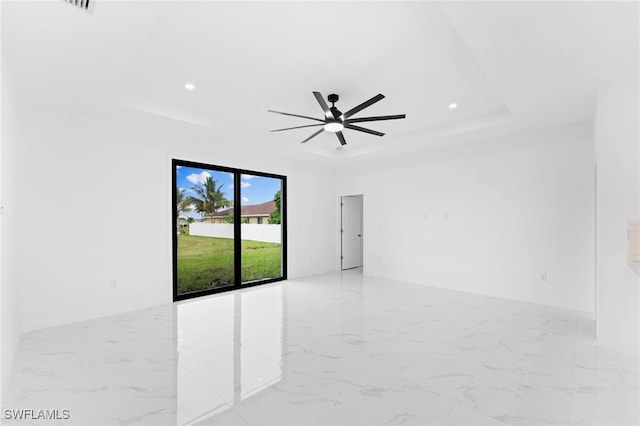 unfurnished room featuring ceiling fan and a raised ceiling