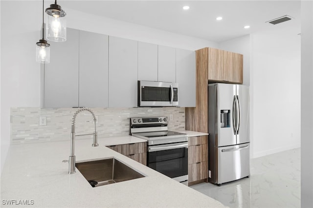 kitchen featuring pendant lighting, sink, white cabinets, decorative backsplash, and stainless steel appliances