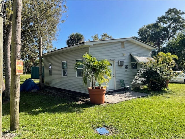 back of property with a wall mounted AC, a lawn, and a patio area