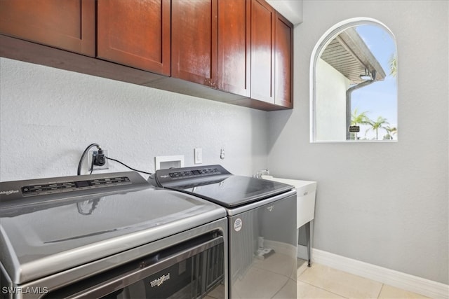 laundry area featuring light tile patterned floors, cabinets, and washing machine and clothes dryer