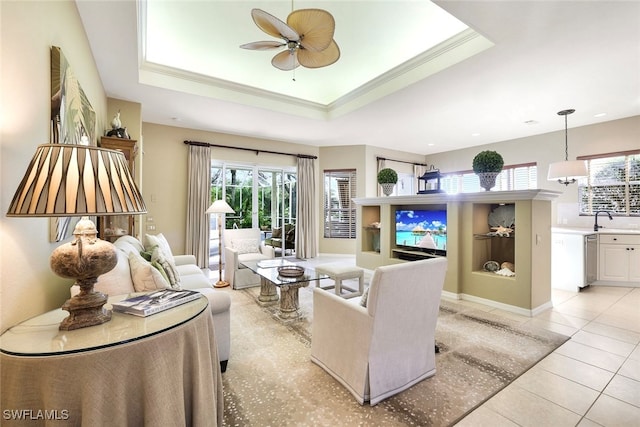 living room featuring ceiling fan, a raised ceiling, sink, and light tile patterned flooring