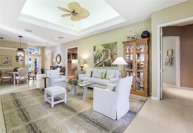 tiled living room featuring ceiling fan and a tray ceiling