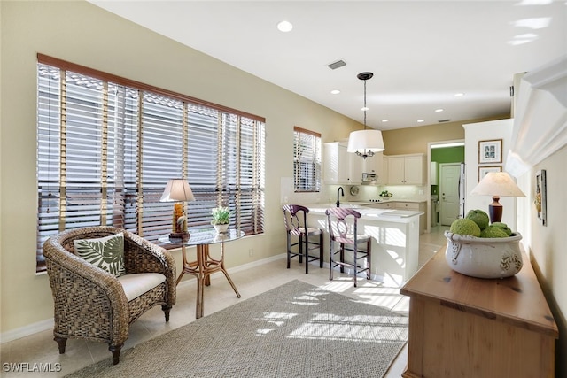 kitchen featuring white cabinetry, kitchen peninsula, a breakfast bar area, light tile patterned floors, and decorative light fixtures