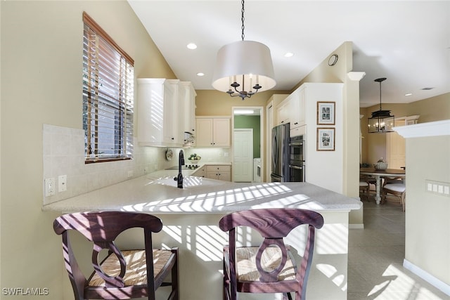 kitchen featuring white cabinets, kitchen peninsula, hanging light fixtures, and a chandelier