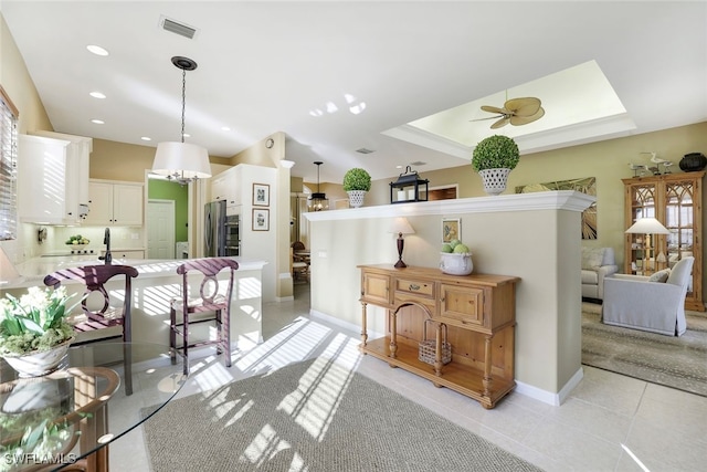 kitchen featuring stainless steel refrigerator, hanging light fixtures, white cabinets, kitchen peninsula, and ceiling fan