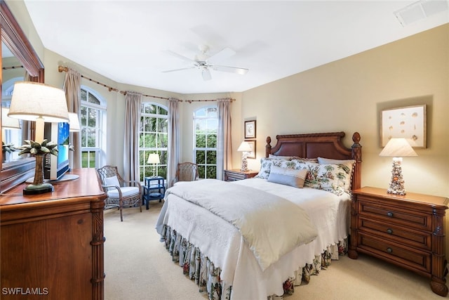 bedroom featuring multiple windows, light colored carpet, and ceiling fan