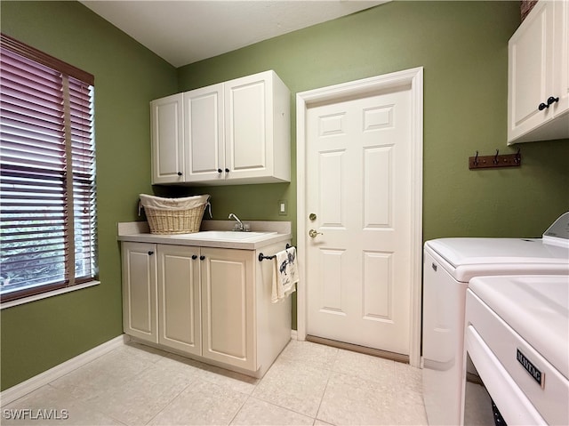 clothes washing area featuring separate washer and dryer, cabinets, sink, and light tile patterned floors