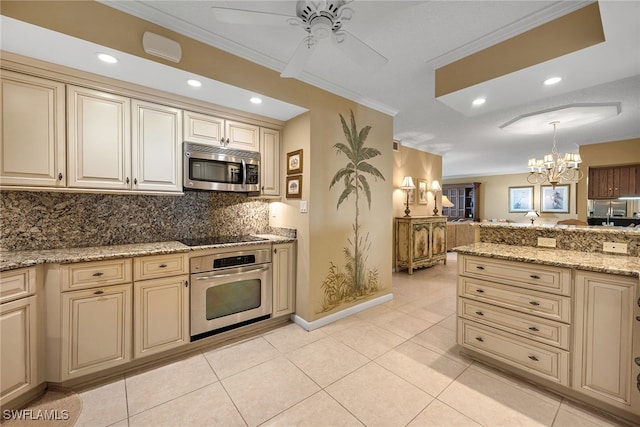 kitchen featuring appliances with stainless steel finishes, decorative light fixtures, cream cabinets, and crown molding