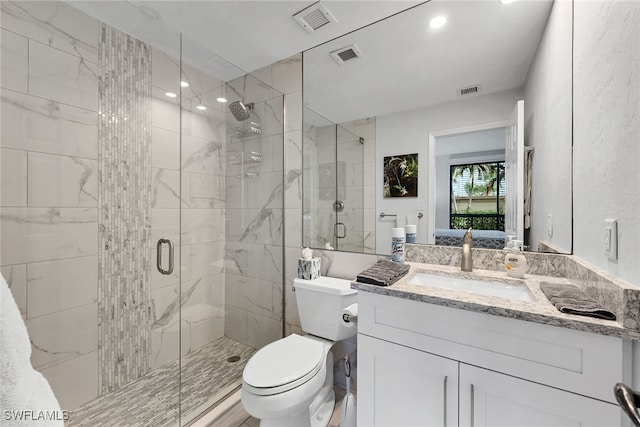 bathroom featuring vanity, toilet, and a shower with door