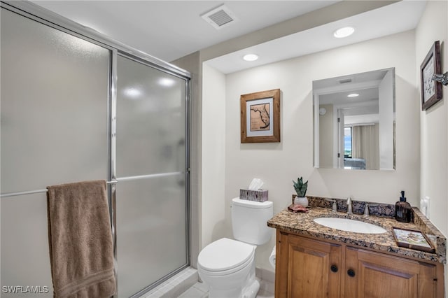 bathroom with tile patterned floors, vanity, a shower with shower door, and toilet