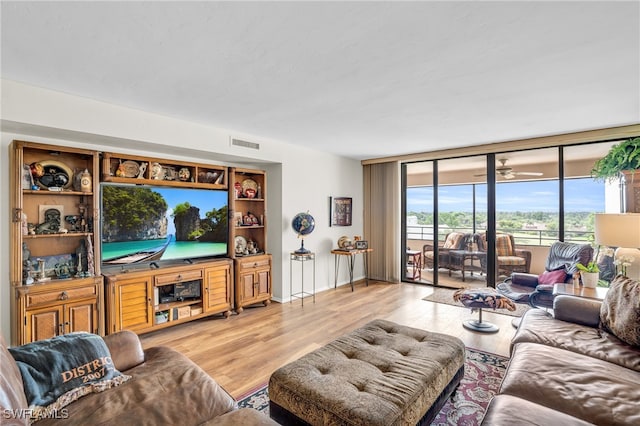 living room featuring ceiling fan, floor to ceiling windows, and light hardwood / wood-style flooring