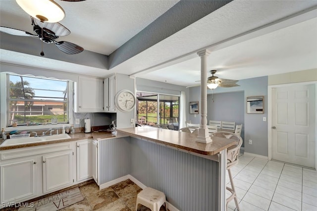 kitchen featuring white cabinetry, kitchen peninsula, a breakfast bar area, and sink