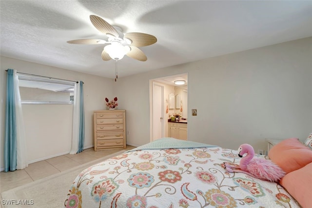 bedroom featuring a textured ceiling, ensuite bath, ceiling fan, and light tile patterned floors