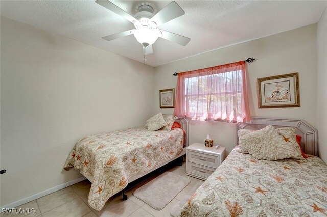 bedroom with a textured ceiling, light tile patterned floors, and ceiling fan