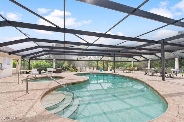 outdoor pool with a lanai, an in ground hot tub, and a patio