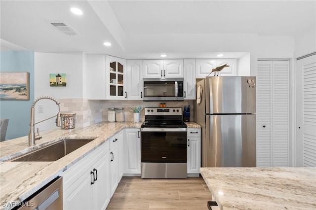 kitchen featuring light hardwood / wood-style floors, light stone counters, white cabinets, sink, and appliances with stainless steel finishes