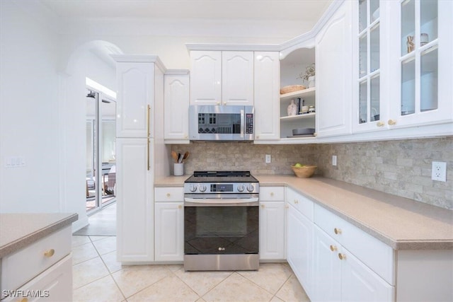 kitchen featuring stainless steel appliances, white cabinetry, light tile patterned floors, and tasteful backsplash