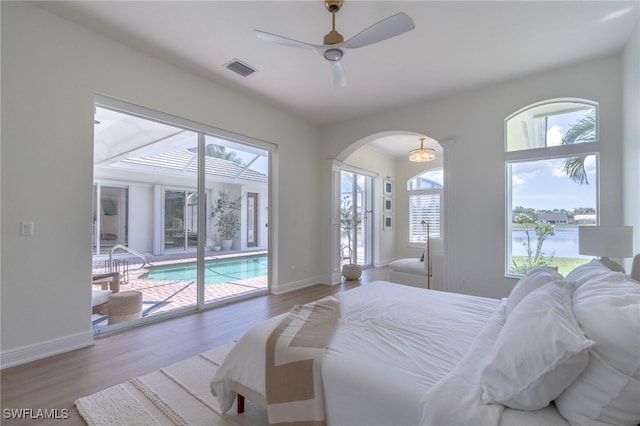 bedroom with access to exterior, wood-type flooring, and multiple windows