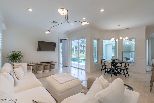 living room with light tile patterned floors, ornamental molding, and a notable chandelier