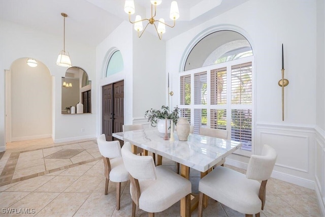 dining space featuring light tile patterned flooring, an inviting chandelier, and high vaulted ceiling