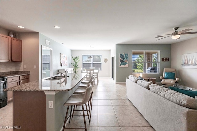 kitchen featuring sink, decorative light fixtures, plenty of natural light, and an island with sink