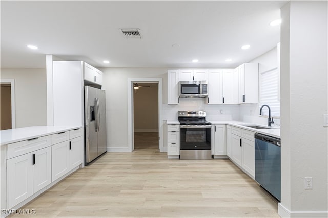 kitchen featuring white cabinets, sink, stainless steel appliances, and light hardwood / wood-style flooring