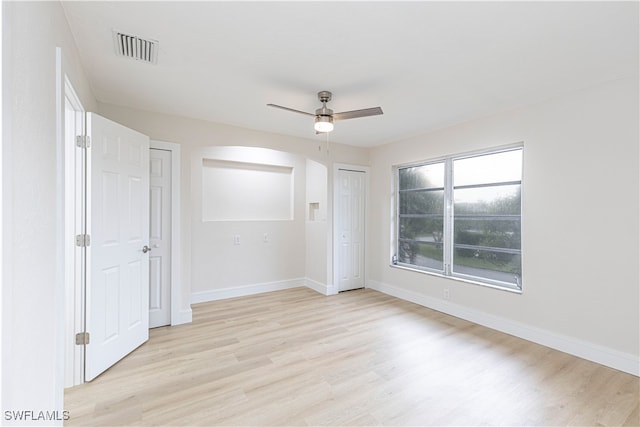 empty room with visible vents, baseboards, light wood-style floors, and ceiling fan