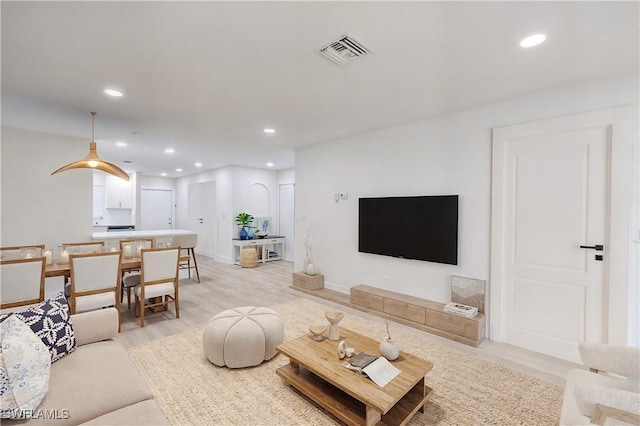 living room with visible vents, recessed lighting, light wood-type flooring, and baseboards