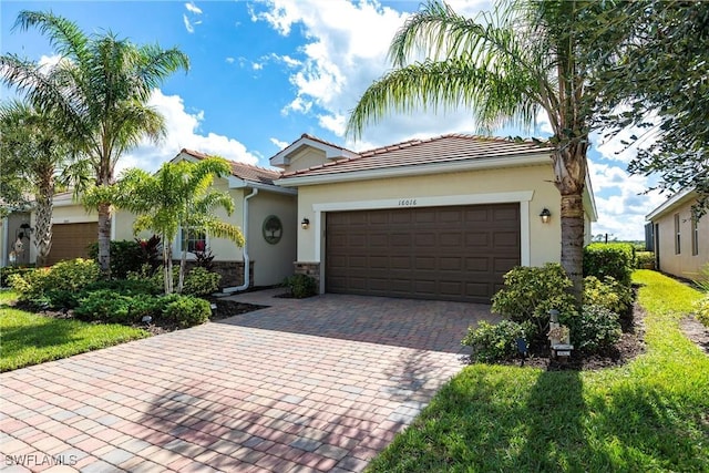 single story home featuring decorative driveway, a tile roof, an attached garage, and stucco siding