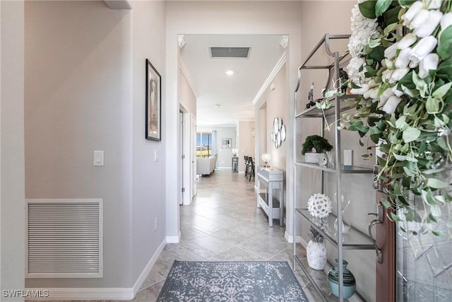 hallway featuring light tile patterned floors, baseboards, visible vents, and crown molding