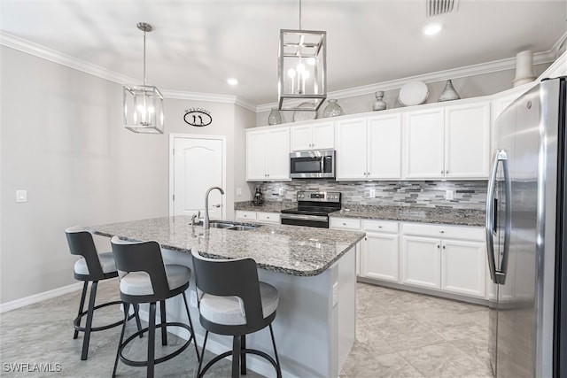 kitchen featuring hanging light fixtures, appliances with stainless steel finishes, a sink, and a kitchen island with sink