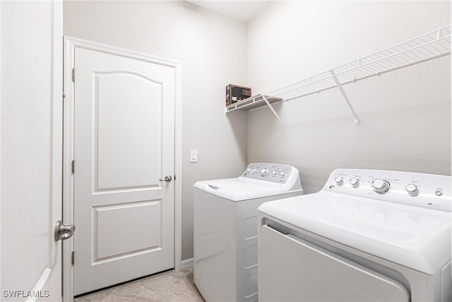 clothes washing area featuring laundry area, light tile patterned flooring, and washing machine and clothes dryer