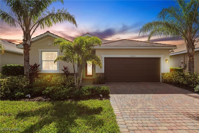 view of front facade featuring a garage, decorative driveway, and stucco siding